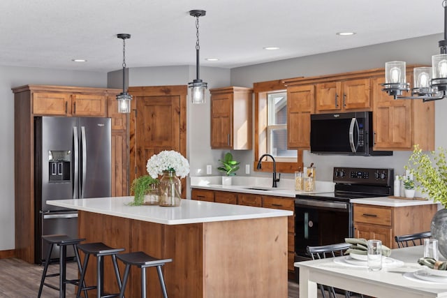 kitchen featuring stainless steel fridge with ice dispenser, decorative light fixtures, a center island, and black range with electric stovetop