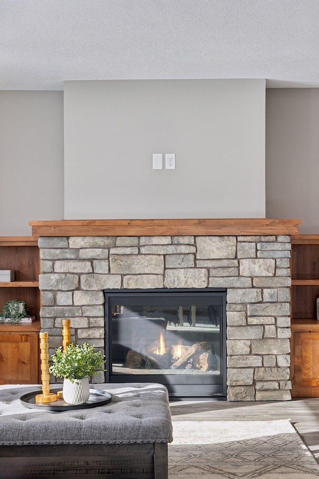 interior details featuring a stone fireplace, hardwood / wood-style floors, and a textured ceiling