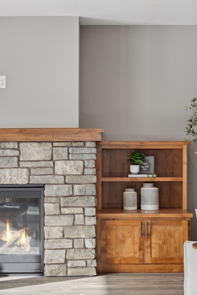 room details featuring hardwood / wood-style flooring, a stone fireplace, and a textured ceiling