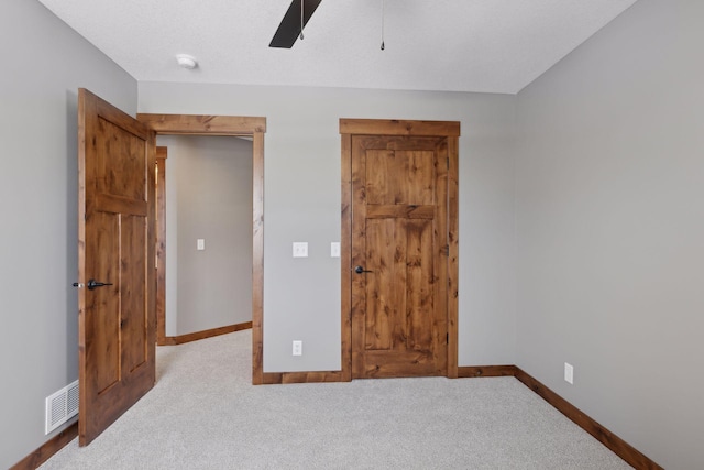 unfurnished bedroom featuring ceiling fan, light colored carpet, and a textured ceiling