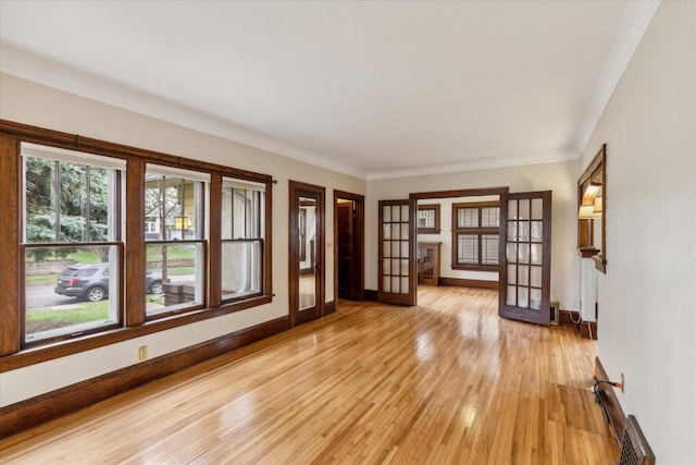 spare room with ornamental molding, french doors, and light wood-type flooring