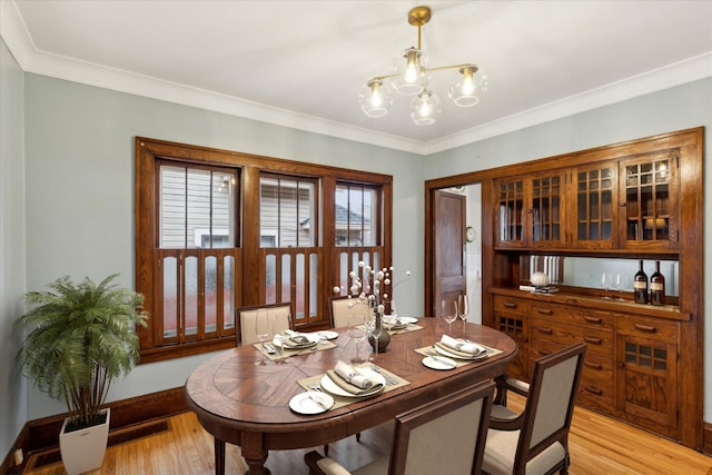 dining room featuring light wood-type flooring, a chandelier, and crown molding