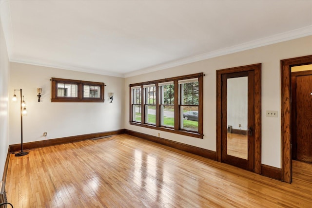 spare room with ornamental molding and light hardwood / wood-style flooring