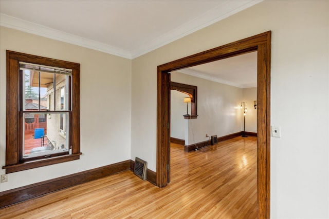 spare room featuring ornamental molding and light wood-type flooring