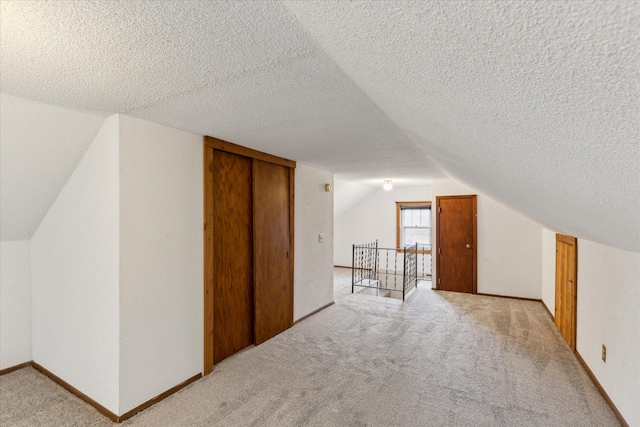 bonus room featuring a textured ceiling, lofted ceiling, and light colored carpet