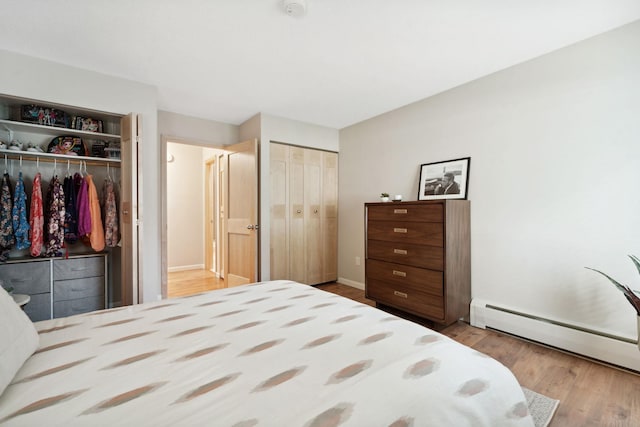 bedroom with baseboard heating and light hardwood / wood-style floors