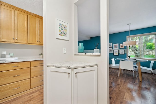 kitchen featuring hardwood / wood-style floors, light brown cabinetry, and hanging light fixtures