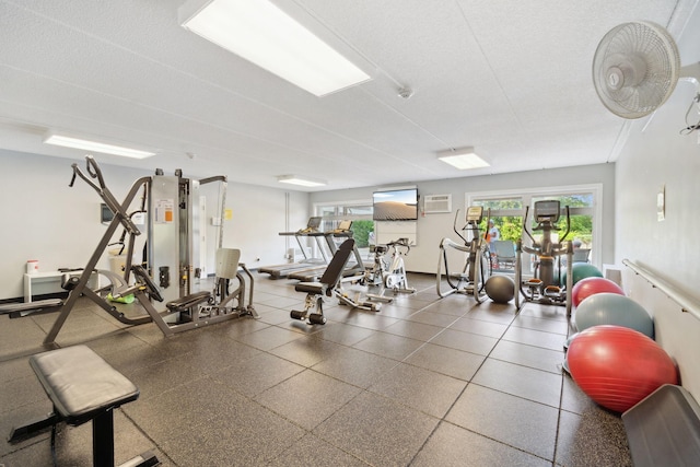 exercise room featuring a wall mounted air conditioner and a textured ceiling