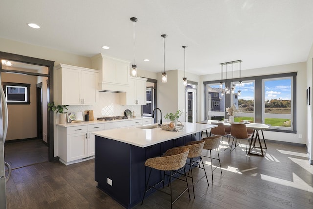 kitchen with white cabinetry, sink, an island with sink, and hanging light fixtures