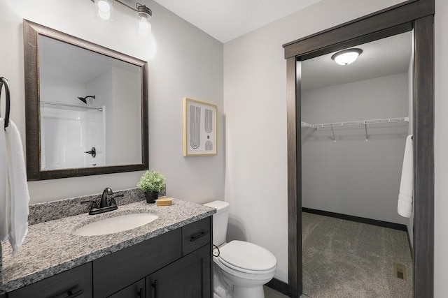 bathroom with vanity, toilet, walk in shower, and a textured ceiling