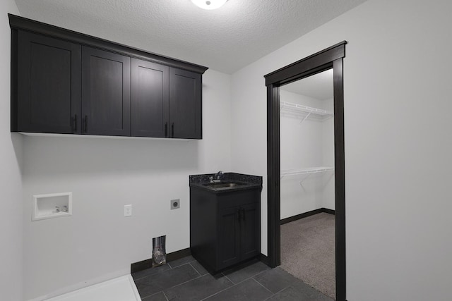 laundry room with cabinets, a textured ceiling, hookup for a washing machine, hookup for an electric dryer, and sink