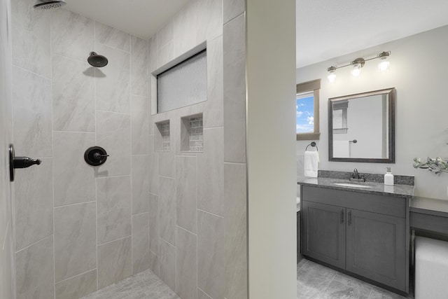 bathroom with a tile shower and vanity