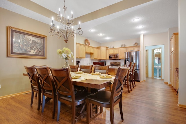 dining room with sink, light hardwood / wood-style flooring, and an inviting chandelier