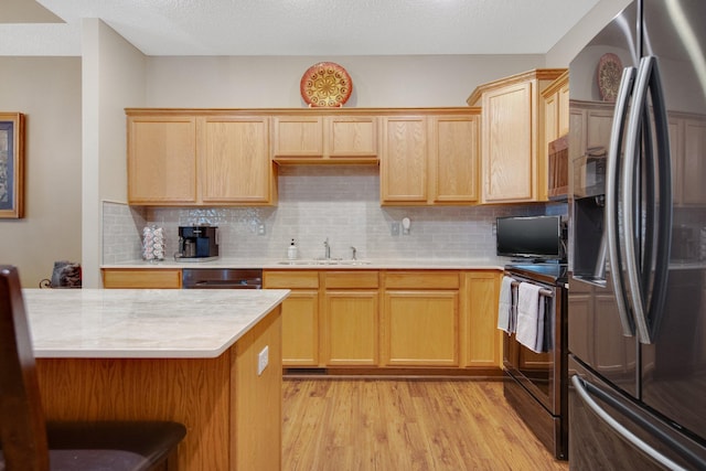 kitchen with sink, light brown cabinets, stainless steel appliances, backsplash, and light hardwood / wood-style floors