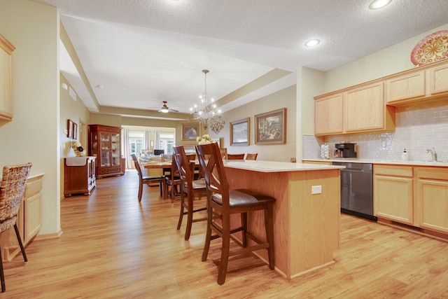 kitchen featuring a center island, hanging light fixtures, stainless steel dishwasher, decorative backsplash, and light hardwood / wood-style floors