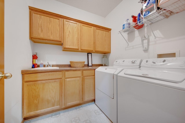 clothes washing area with separate washer and dryer, sink, and cabinets