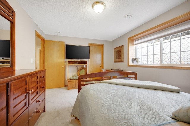 bedroom with light colored carpet and a textured ceiling