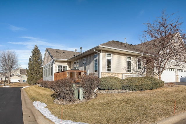 view of side of property with a lawn, a wooden deck, and a garage