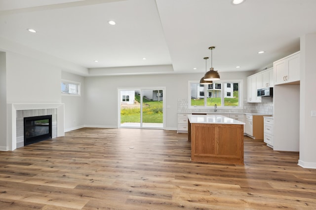 kitchen featuring white cabinets, hanging light fixtures, light wood-type flooring, a fireplace, and a kitchen island