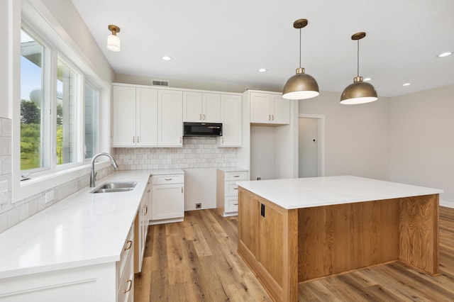 kitchen featuring white cabinets, a center island, hanging light fixtures, and sink