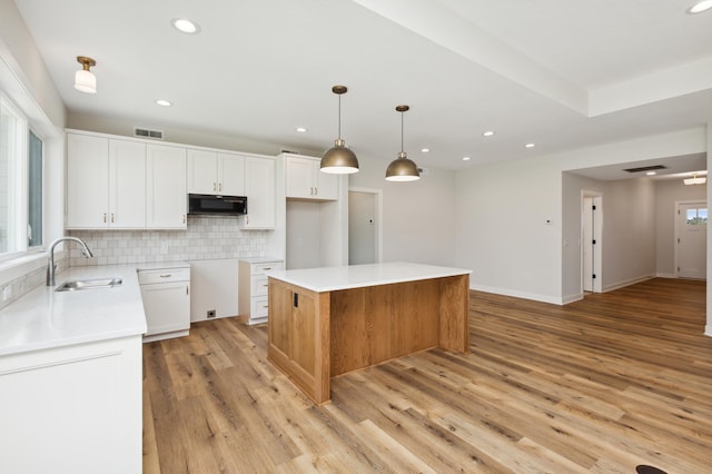 kitchen with pendant lighting, a center island, backsplash, sink, and white cabinetry