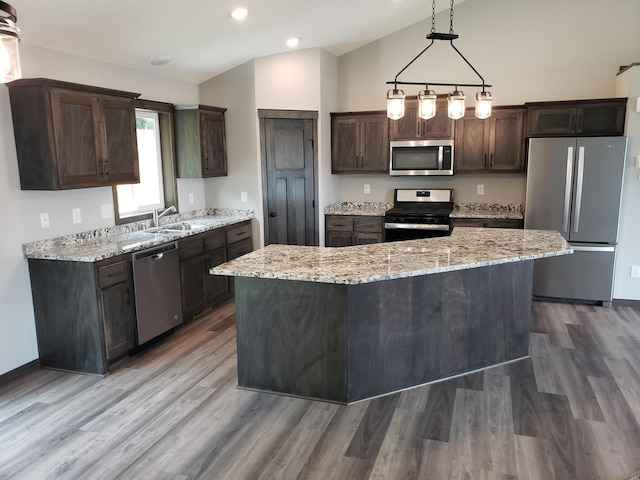 kitchen with a center island, stainless steel appliances, decorative light fixtures, sink, and hardwood / wood-style flooring