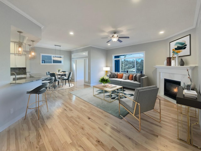 living room featuring light hardwood / wood-style flooring, ceiling fan, and crown molding