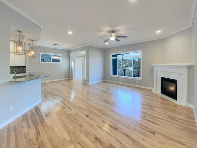 unfurnished living room featuring ceiling fan, light hardwood / wood-style floors, a premium fireplace, and crown molding