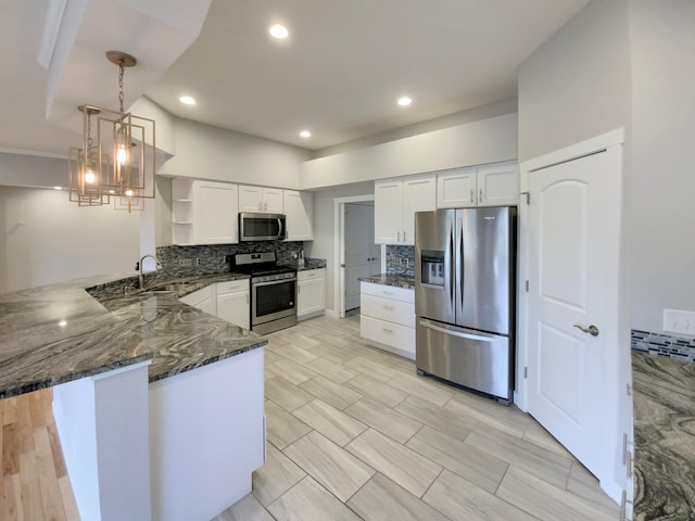 kitchen featuring white cabinets, appliances with stainless steel finishes, tasteful backsplash, decorative light fixtures, and kitchen peninsula