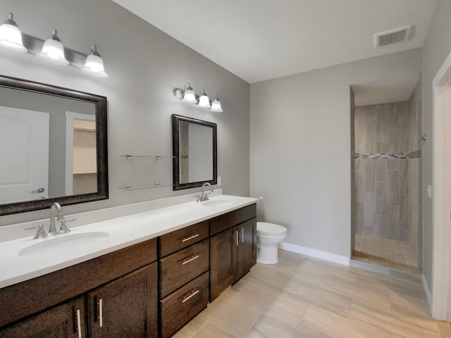 bathroom with tiled shower, vanity, tile patterned floors, and toilet