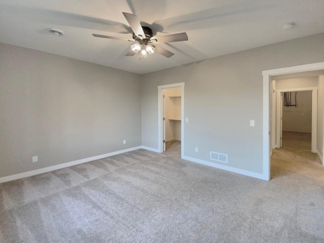 unfurnished bedroom with ceiling fan, light colored carpet, a walk in closet, and a closet