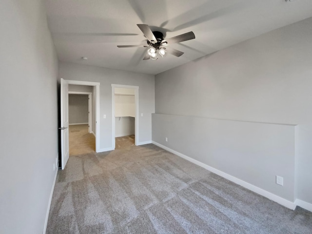 unfurnished bedroom with a spacious closet, a closet, ceiling fan, and light colored carpet