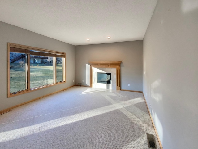 unfurnished living room featuring light carpet and a textured ceiling