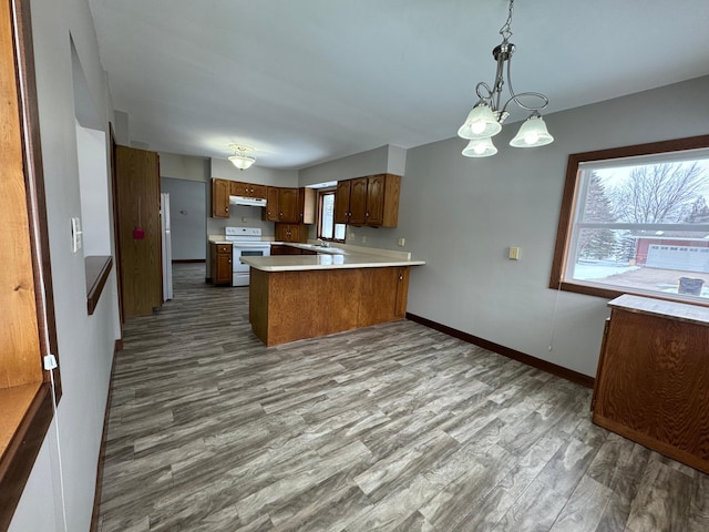 kitchen featuring white appliances, an inviting chandelier, light hardwood / wood-style floors, hanging light fixtures, and kitchen peninsula