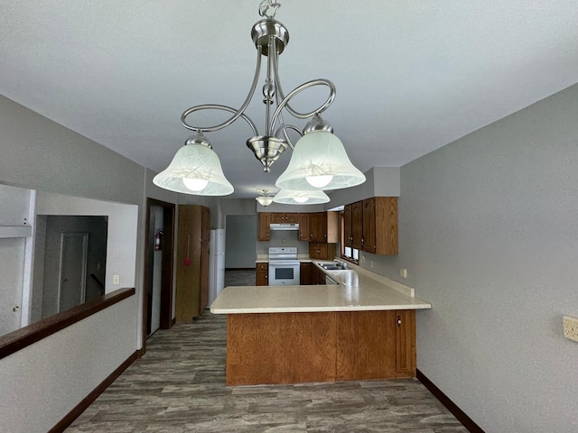 kitchen featuring kitchen peninsula, dark hardwood / wood-style floors, white electric range oven, hanging light fixtures, and a chandelier