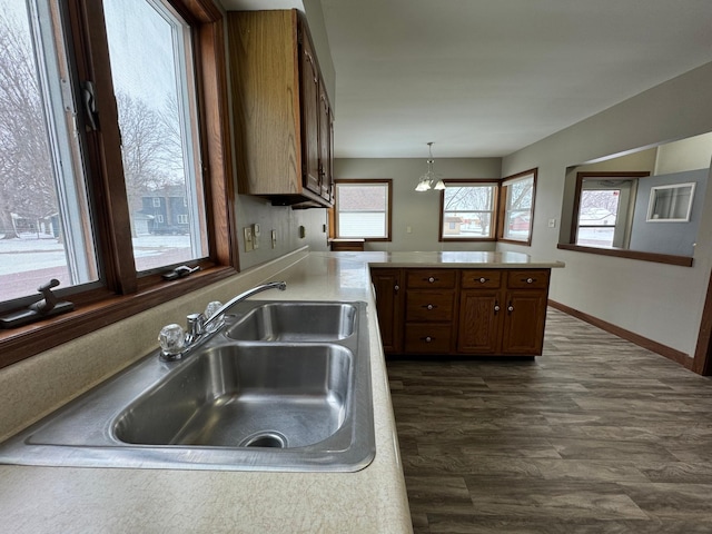 kitchen featuring dark hardwood / wood-style flooring, sink, hanging light fixtures, kitchen peninsula, and a notable chandelier