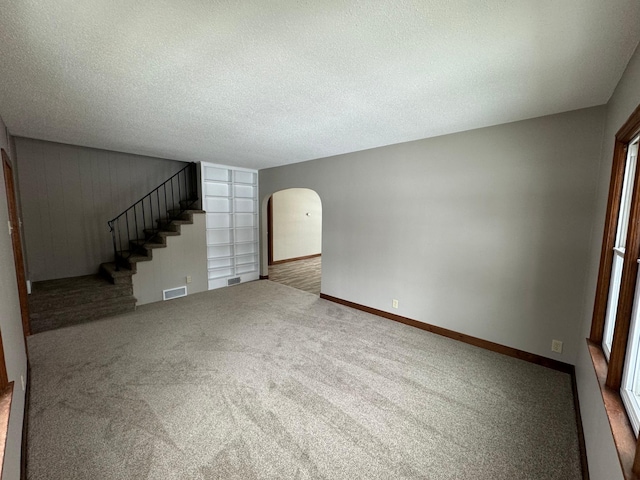 unfurnished living room featuring carpet floors and a textured ceiling