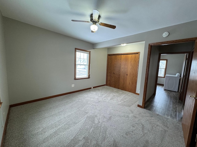 unfurnished bedroom with washer / dryer, a closet, dark carpet, and ceiling fan