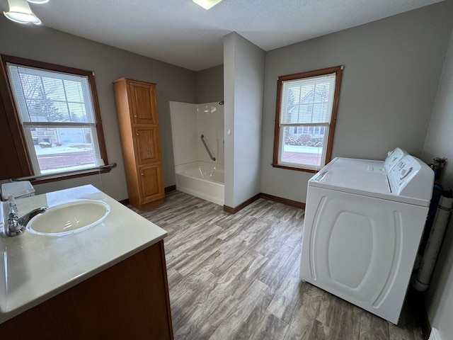 bathroom with vanity,  shower combination, separate washer and dryer, and a healthy amount of sunlight