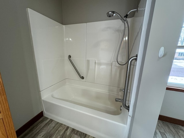 bathroom with wood-type flooring and washtub / shower combination