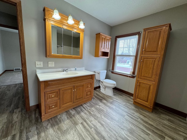 bathroom with toilet, vanity, and hardwood / wood-style flooring