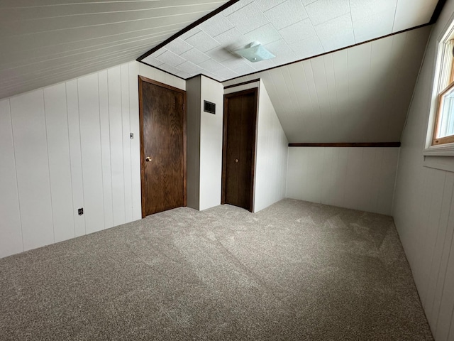 additional living space with wood walls, carpet, and lofted ceiling