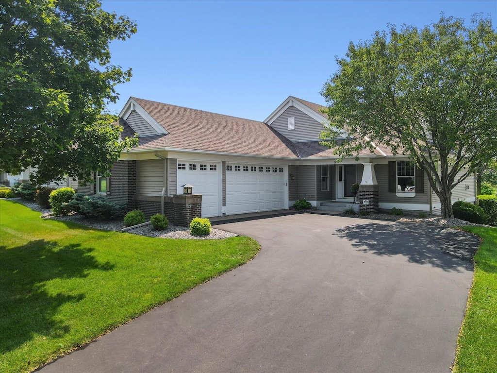 view of front of home with a garage, a shingled roof, driveway, and a front yard