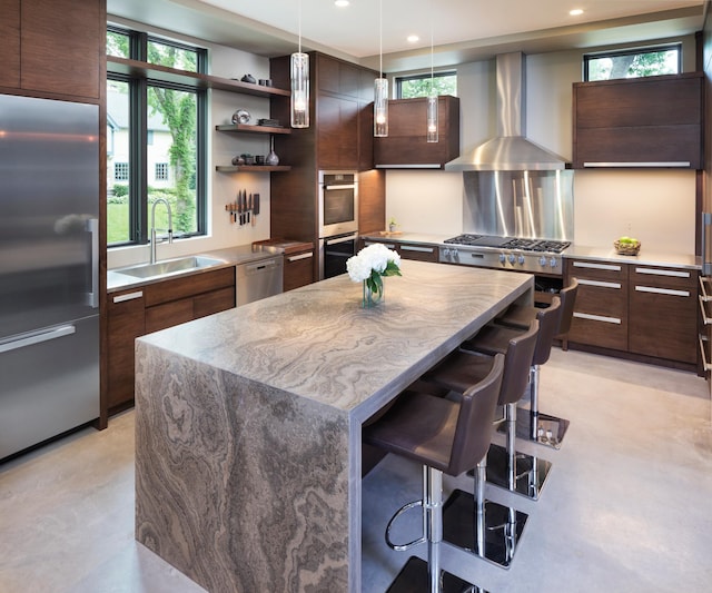 kitchen featuring appliances with stainless steel finishes, a sink, wall chimney range hood, and modern cabinets