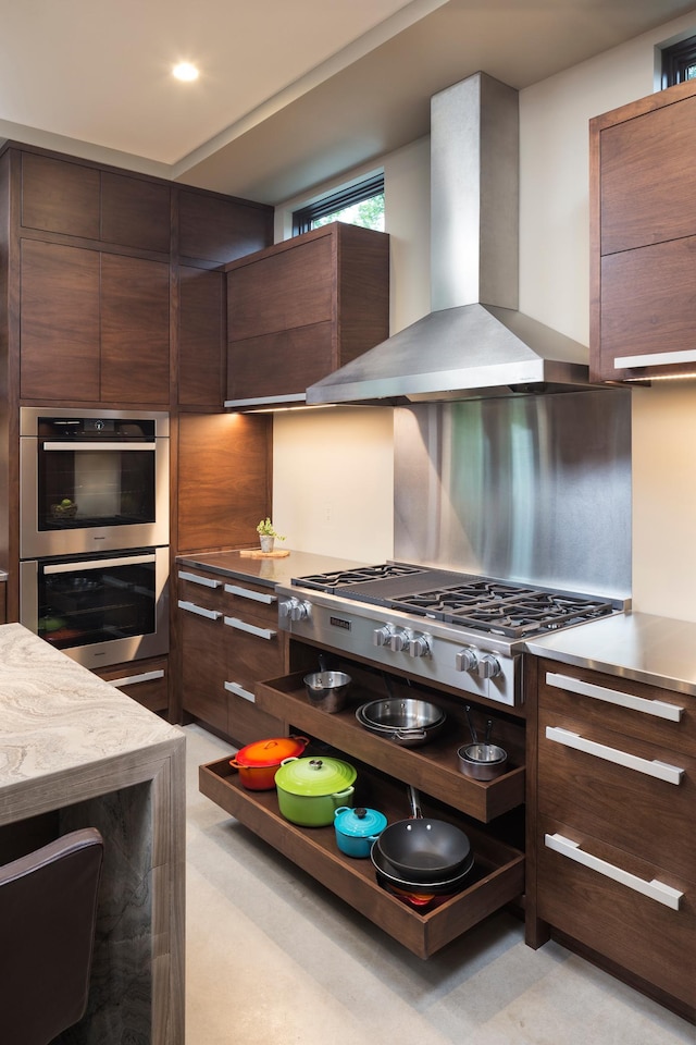 kitchen featuring recessed lighting, light countertops, decorative backsplash, appliances with stainless steel finishes, and wall chimney range hood