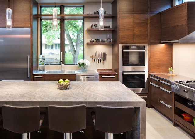 kitchen with hanging light fixtures, a kitchen bar, stainless steel appliances, and open shelves