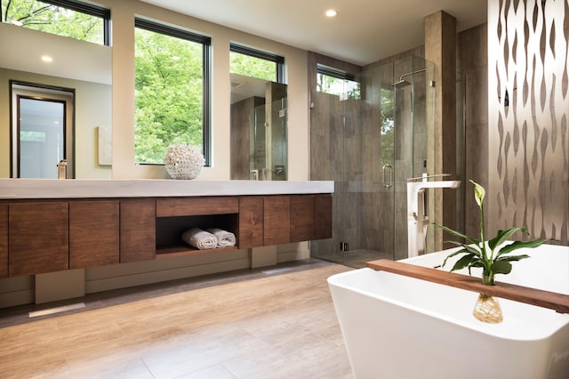 bathroom featuring a stall shower, a freestanding tub, vanity, and recessed lighting