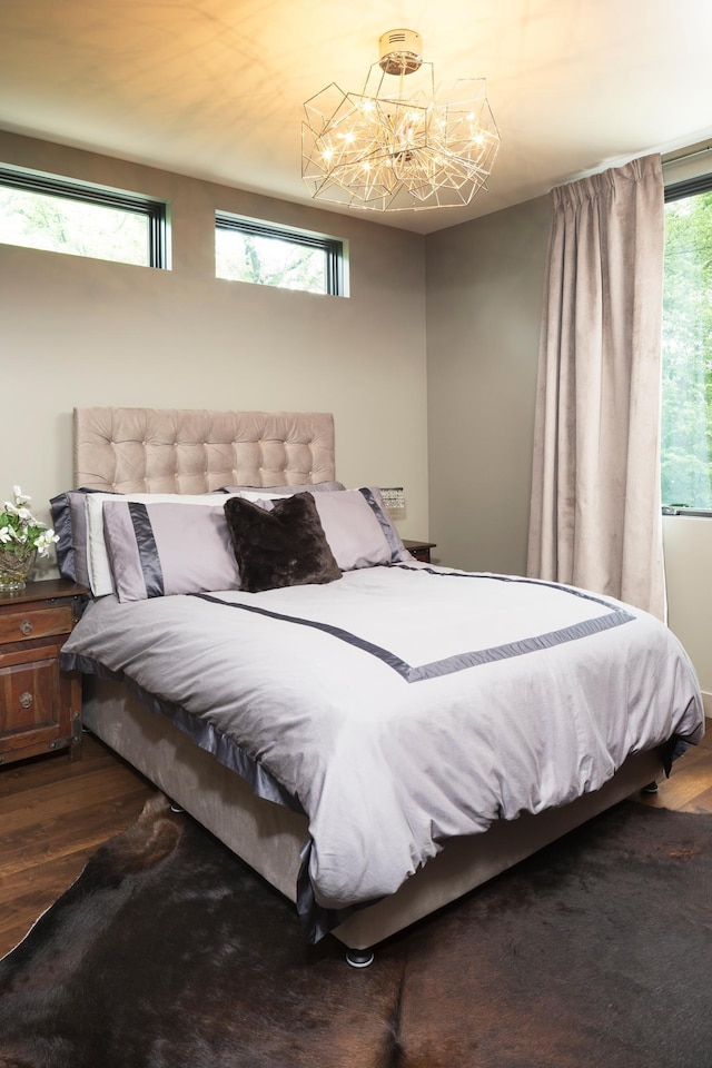 bedroom with wood finished floors and an inviting chandelier