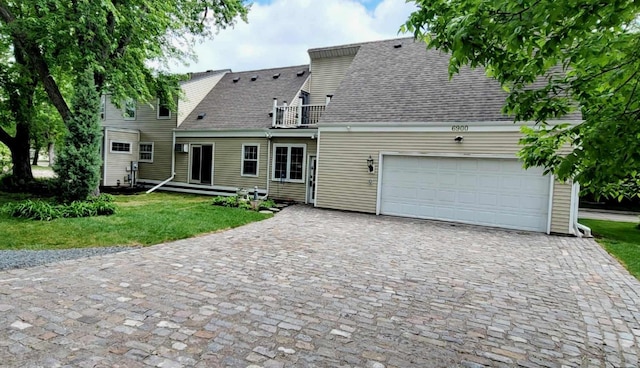 view of front of property featuring a garage, a front lawn, and a balcony