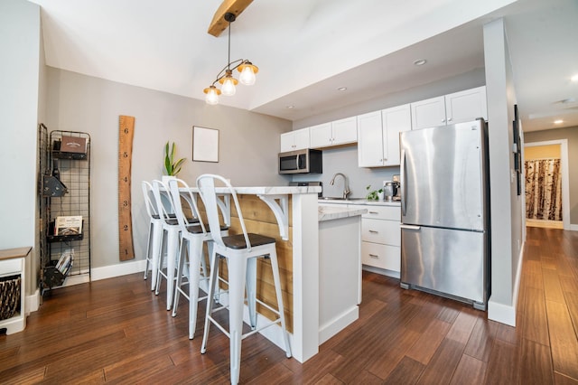 kitchen featuring pendant lighting, sink, a breakfast bar area, stainless steel appliances, and white cabinets